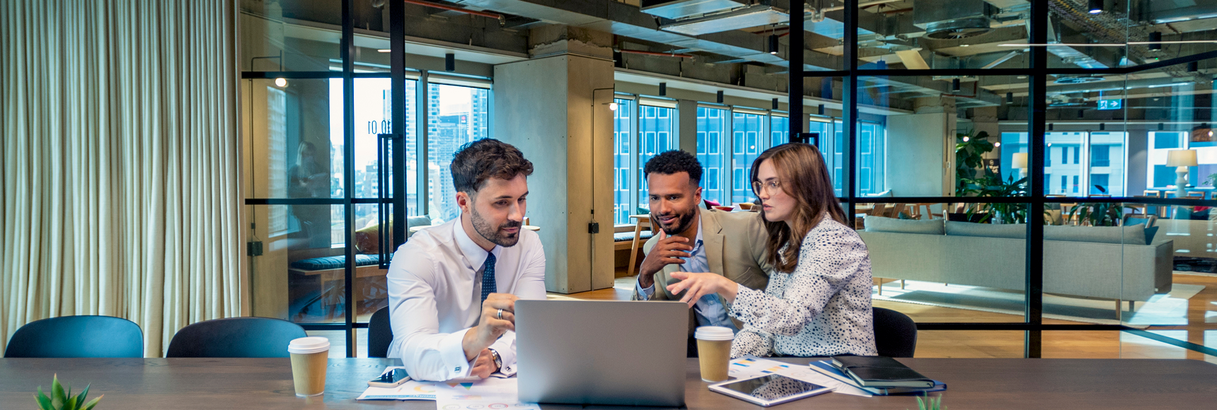 Three colleagues discussing work at desk.